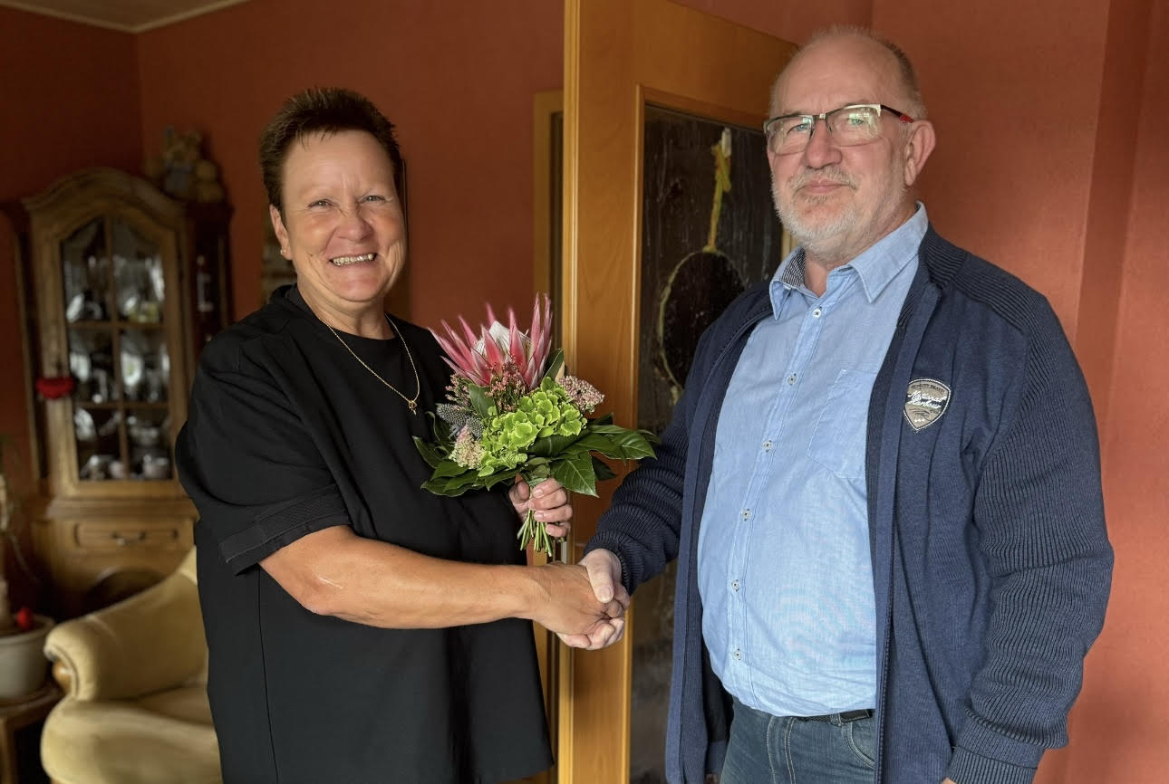 B. Arkenau überreicht S. Engelbrecht einen Blumenstrauß