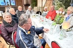 An Tischen sitzen Mitglieder in einer Runde zusammen und warten auf die Berichte.