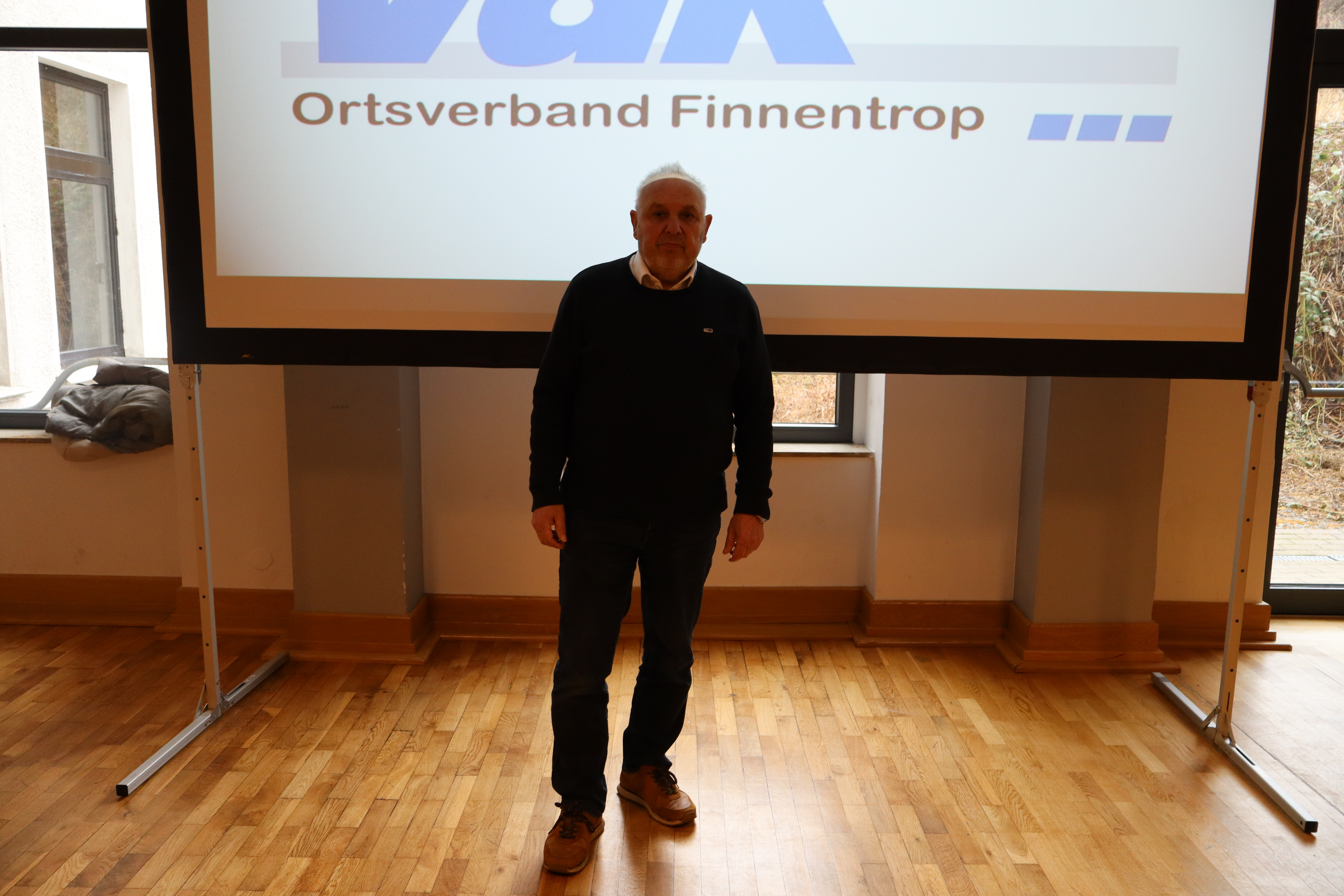 Vorsitzender A. Hasenau vor der Leinwand vor der JHV