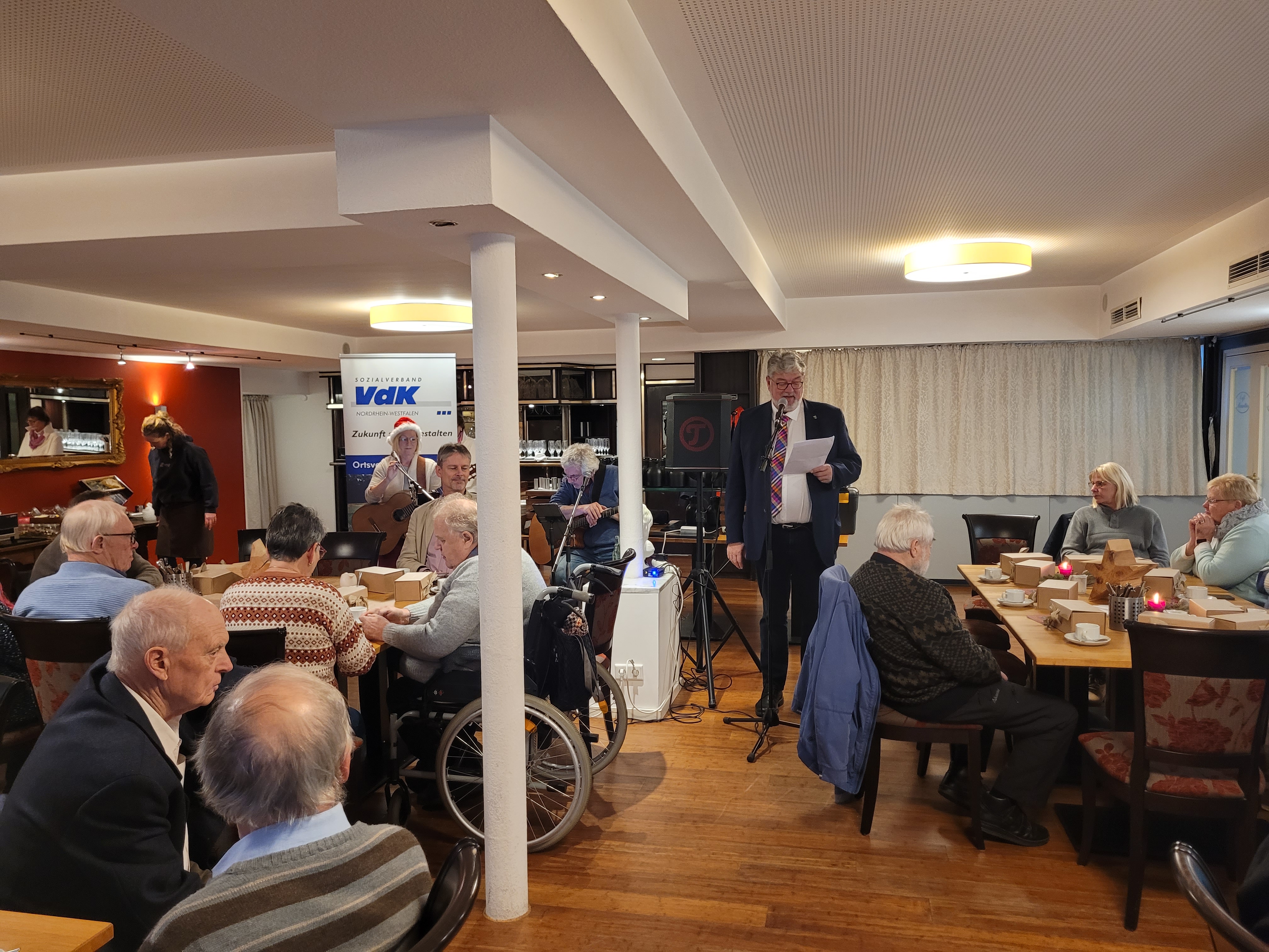 Klaus Meiers bei der Begrüßung zwischen den Mitgliedern im Saal von Café Mauritius