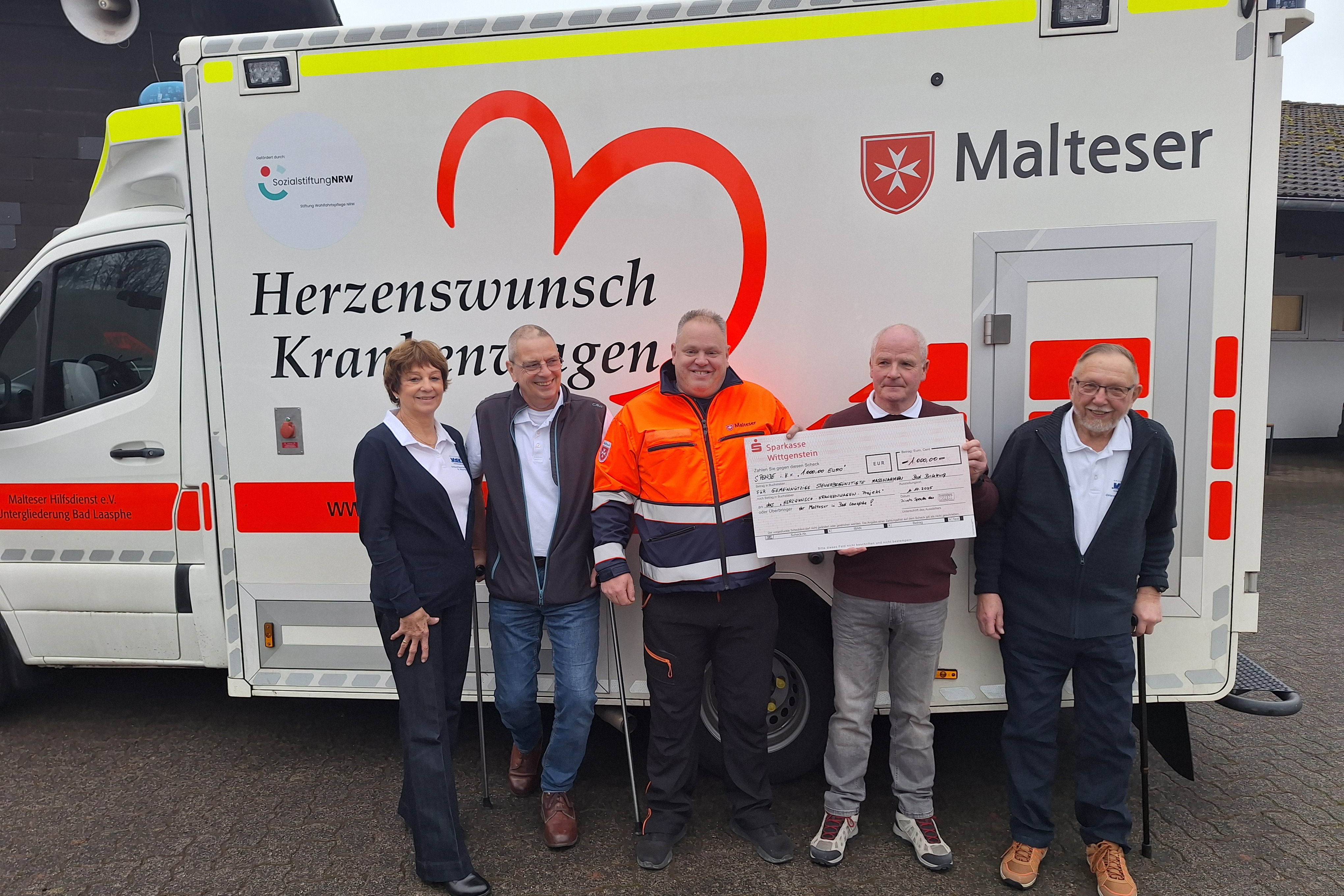 Einige Vorstandsmitglieder des VdK-Ortsverbandes stehen gemeinsam mit Michael Hermann bei der Spendenübergabe vor dem Herzenswunsch-Krankenwagen der Malteser