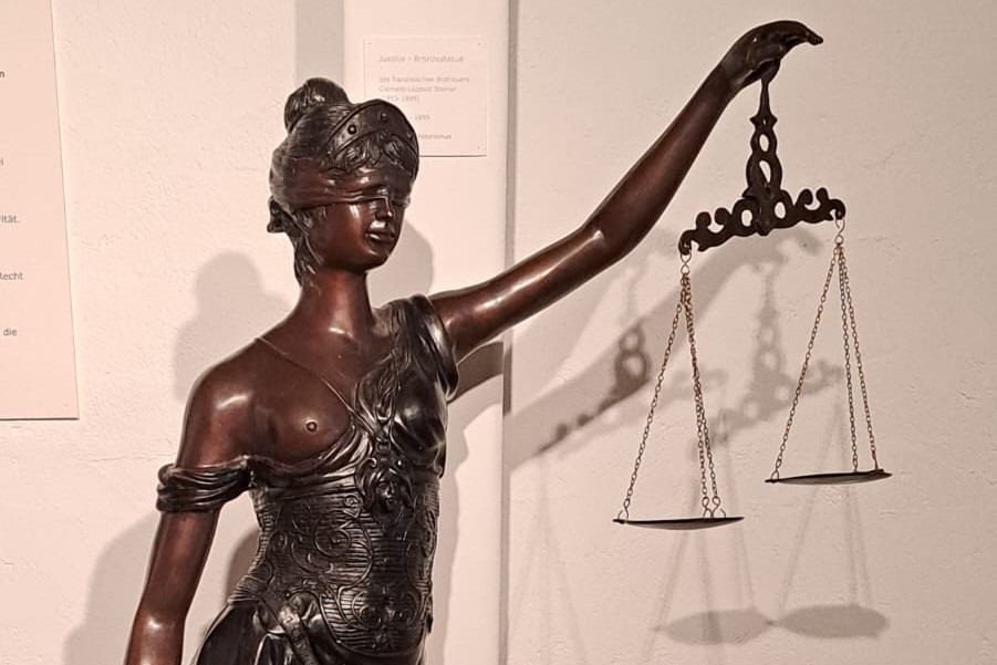 Bronzeskulptur der Justizia, einer Frau mit Waage und Schwert.
