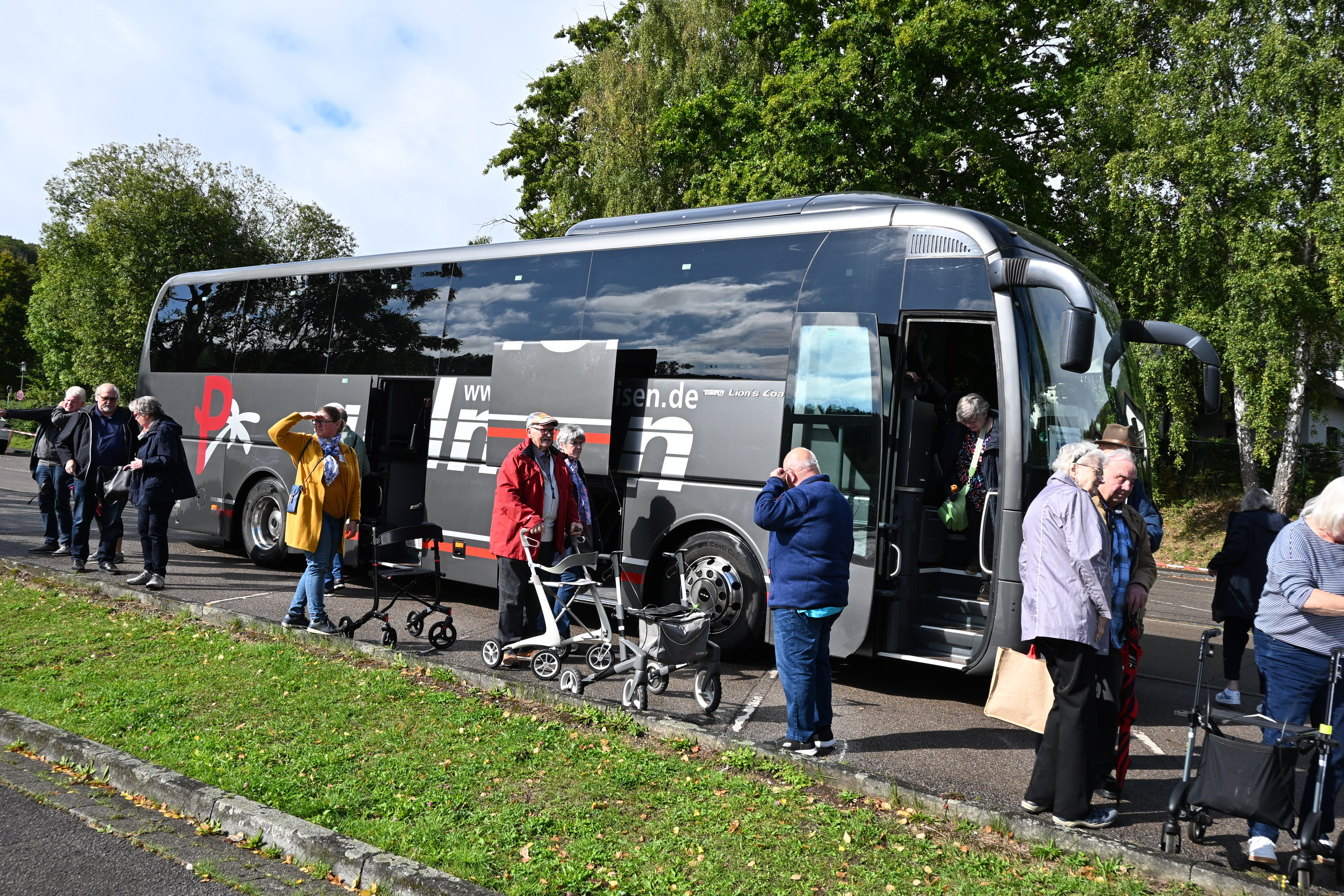 Ein Reisebuss aus dem Personen aussteigen und viele mit Rollator