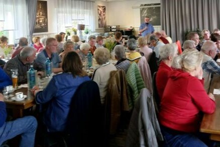 Viele Menschen sitzen versammelt an Tischen in einem Lokal