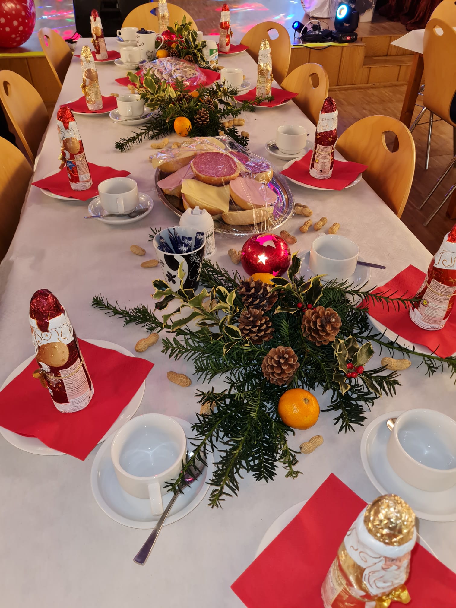 Weihnachtliche eingedeckter Tisch mit Schokoladennikolaus, belegten Brötchen und Tannengesteck