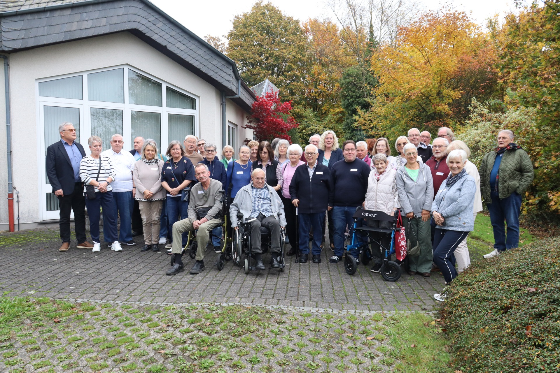 Mehrere Menschen stehen für ein Gruppenbild draußen vor dem Haus zusammen.